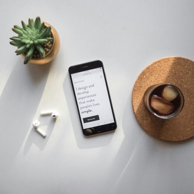 post-2014 iPhone beside Apple AirPods and succulent plant on white surface for Socials Code